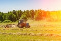 An old tractor turns over the mowed hay on a Sunny summer morning for better drying. Fodder for cows for the winter Royalty Free Stock Photo