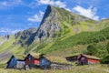 Old traditional farm houses with grass on the roof in the middle of valley with big mountain behind