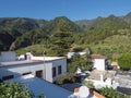 Old traditional houses at village Las Nieves with green mountains and subtropical vegetation, blue sky background. La