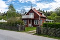 Old traditional red wooden house in Sweden. Two storey small house. Traditional wooden Swedish fence around. Green hedge. Royalty Free Stock Photo