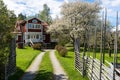 Old traditional red wooden house in Sweden. Two storey villa cottage. Traditional wooden Swedish fence around. Blooming apple tree Royalty Free Stock Photo