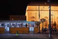 Old train driving in the street of Budapest with a lit building in the background at night Royalty Free Stock Photo