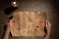 old pirate map drawn on aged paper in hands, candle on the table, treasure hunt and adventure search concept Royalty Free Stock Photo