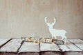 Old tree log with fairy christmas lights and reindeer on wooden table.selective focus