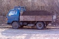 An old truck with a large pile of soil in the back.