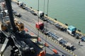 Old trucks in container terminal waiting for loading next to mobile cranes with orange spreader.