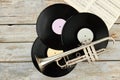 Old trumpet and vinyl records on wooden background.