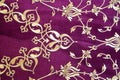 Old Turkish embroidered fabric with golden geometric and floral decorations against a purple background Royalty Free Stock Photo