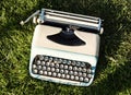 Old turquoise typewriter on the grass Royalty Free Stock Photo