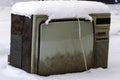 An old TV stands on the street covered with a thick layer of snow