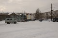 Old two-storied house in winter with snow, cars and trees on the yard. Poverty and misery, North Royalty Free Stock Photo