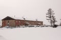 Old two-storied red house in winter with snow, cars and trees on the yard. Poverty and misery, North Royalty Free Stock Photo