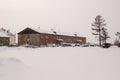 Old two-storied red house in winter with snow, cars and trees on the yard. Poverty and misery, North Royalty Free Stock Photo