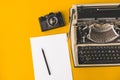Old typewriter, A Vintage Film Camera, A Sheet Of Paper And A Pencil On A Yellow Background, Top View. Creative concept Royalty Free Stock Photo