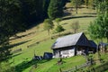 The old Ukrainian hut with a slate roof and a wooden fence in a green fiel Royalty Free Stock Photo