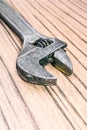 Old universal adjustable wrench on a wooden background. Closeup Bench tool.