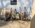 Old unused and broken wheelbarrows placed against the wall in a row outside