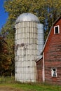 Old unused concrete stave silo by a red barn