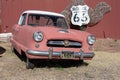 Old urban small car abandoned on a farm, it's a red Nash Metropolitan