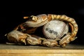Old used baseball glove with a ball on a wood bench Royalty Free Stock Photo