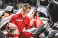 Old used car part warehouse worker checking inventory in garage. Staff worker working in recycle motor junkyard auto parts