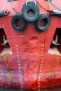 Old used car tires as fender on a shipboard. Red ship hull with