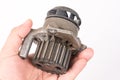 Old used dirty car water pump in the hand above white background