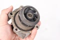 Old used dirty car water pump in the hand above white background