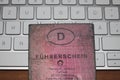 old used, dirty pink German driving license on a white keyboard