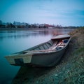 An old used fishing boat stranded on the muddy bank of the Sava River at dusk with clouds in the sky. Water transport in Bosanski Royalty Free Stock Photo