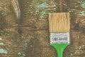 Old used green paintbrush on rustic wooden board