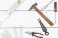 Old used hammer, pliers, libella, measuring meter, nonius and screwdriver with copy space on the white wooden board table. Do it