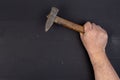 Old used hammer with wooden handle in the male hand above black wooden boards table. DIY concept with copy space above black Royalty Free Stock Photo