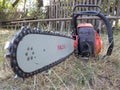 Old used petrol chainsaw covered with sawdust after cutting work, on grass in countryside