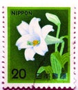 An old used postage stamp printed in Japan shows White Trumpet Lily Lilium longiflorum 1982 Amaryllis Belladonna flower