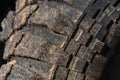 Old used extreme terrain tire with worn wear-resistant tread. Close-up of black muddy off-road tire