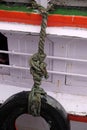 Old used tire with rope on the side of boat for fender