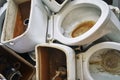 Old used toilet bowls lying on a dump