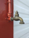 Old and used Vintage faucet isolated. Bronze profile, metallic tap on red and white background wall Royalty Free Stock Photo