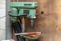 Old vertical green drilling machine with a big red power button and rust on the iron elements in an industrial production workshop Royalty Free Stock Photo