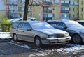 Old veteran dented big hatchback Swedish car silver grey Volvo 850 under snow cover