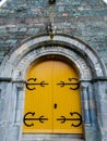 Old vibrant yellow church door saint gargoyle statue