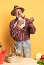 Old village man in straw hat holding chicken and watching at freshly laid eggs Royalty Free Stock Photo