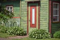 Old village wooden house front yard with red door elements fence and green plants Royalty Free Stock Photo