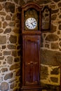 Old vintage antique bronze clock and utensil on wooden shelf, stone wall background. Royalty Free Stock Photo