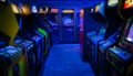 Old Vintage Arcade Video Games in an empty dark gaming room with blue light with glowing displays Royalty Free Stock Photo