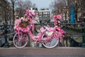 Old vintage bicycle decorated with pink flowers on small bridge in old part of Amsterdam Royalty Free Stock Photo