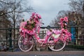 Old vintage bicycle decorated with pink flowers on small bridge in old part of Amsterdam Royalty Free Stock Photo
