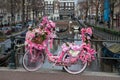 Old vintage bicycle decorated with pink flowers on small bridge in old part of Amsterdam Royalty Free Stock Photo