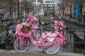 Old vintage bicycle decorated with pink flowers on small bridge in old part of Amsterdam Royalty Free Stock Photo